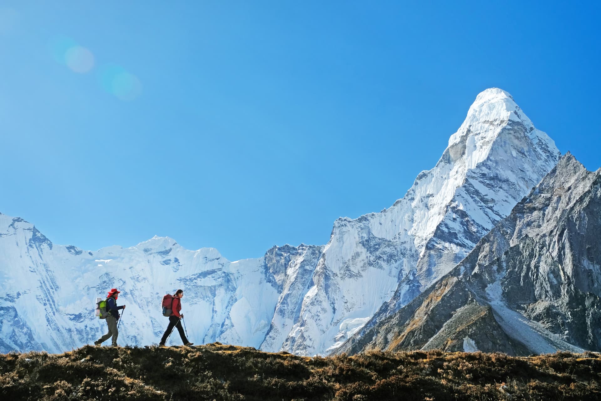 Zwei Trekker auf einem Höhenweg vor der schneebedeckten Ama Dablam in Nepal
